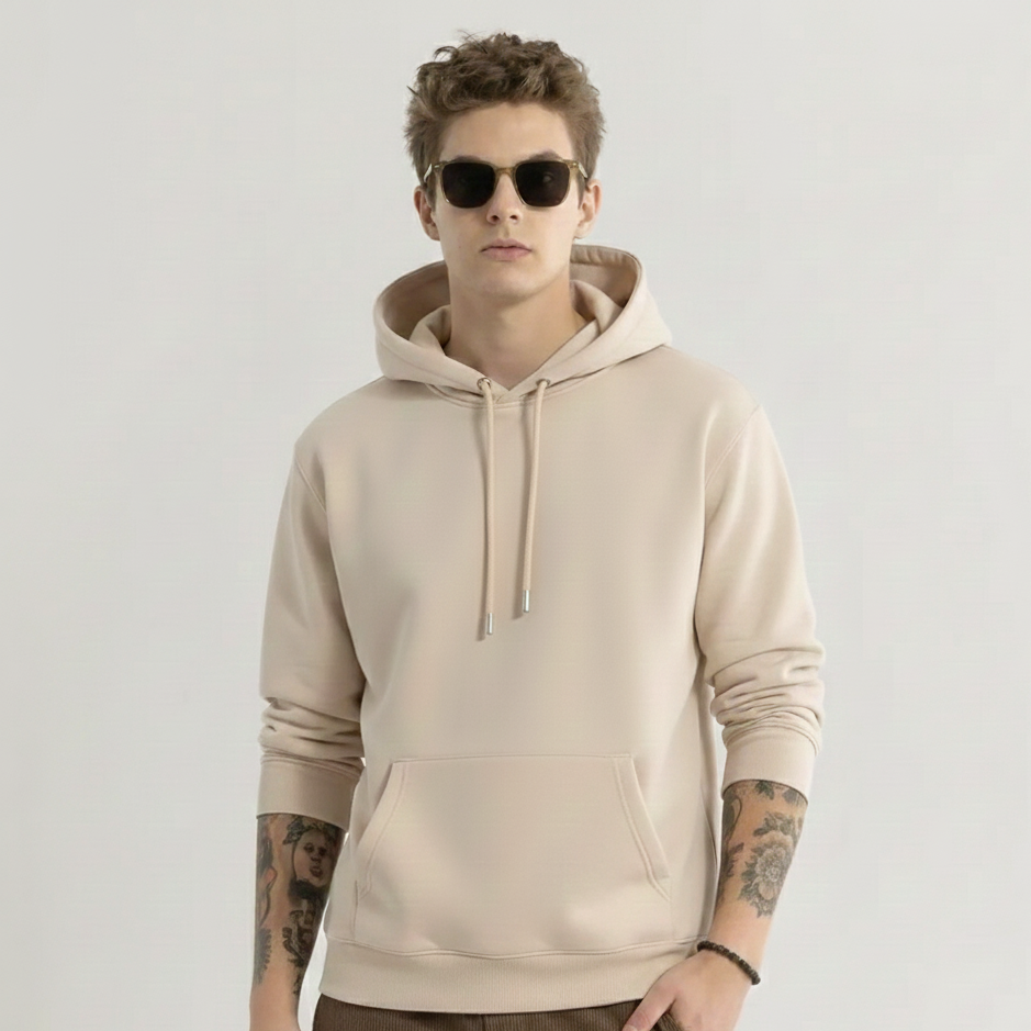 Person wearing a beige hoodie and sunglasses on a plain background